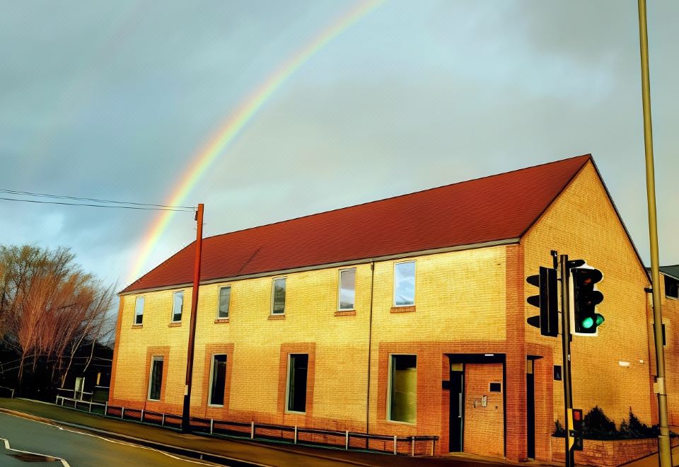 a yellow building with a red roof and a rainbow in the sky , as well as a traffic light and a street sign at The Temple Inn