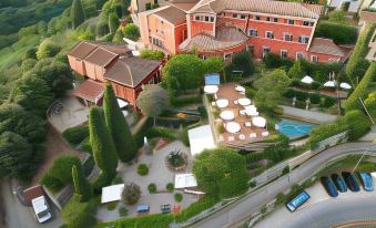 aerial view of a large brick building surrounded by trees , with a swimming pool in the foreground at Hotel Villa Sermolli