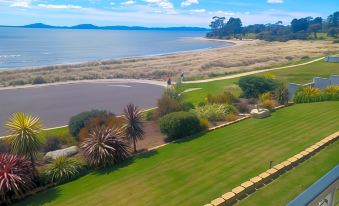 a lush green lawn with a view of the ocean and mountains in the distance at Swansea Motor Inn Tasmania