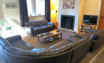 a cozy living room with a large couch , two chairs , and a fireplace , decorated with paintings on the wall at Irton Hall