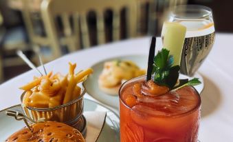 a dining table with a variety of food and drinks , including a burger , fries , and a drink in a glass at The Peppermill Town House Hotel & Restaurant