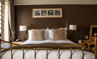 a large bed with a gold headboard and white linens is shown in a bedroom at The New Inn