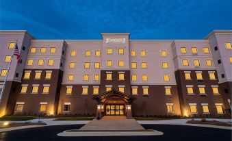 a large hotel building at night , illuminated by lights and surrounded by trees and grass at Staybridge Suites Washington DC East - Largo