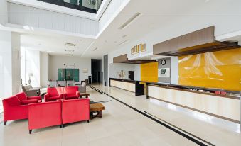 a modern hotel lobby with a red couch and a reception desk , creating a welcoming atmosphere at Raia Hotel & Convention Centre Alor Setar