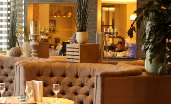 a cozy restaurant with a beige couch and wooden table , white vase , and wooden cabinets at Riverside Lodge Hotel