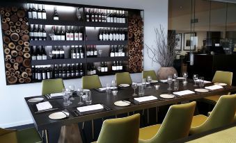 a dining room with a long table covered in white plates and wine glasses , as well as several chairs arranged around it at Mercure Clear Mountain Lodge