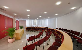 a large conference room with rows of red chairs arranged in a semicircle around a table at Maistra Select Riva Apartments