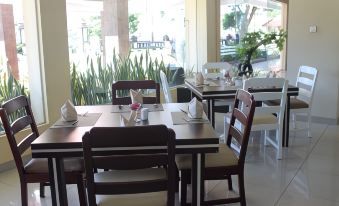 a restaurant with wooden tables and chairs , white napkins on the chairs , and a window view at Khas Parapat