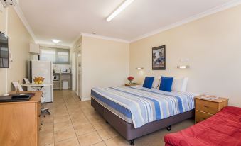 a clean , well - organized bedroom with a bed and a bathroom next to it , along with a couch and a chair at Emu Point Motel