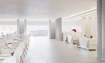 a large , modern dining room with white chairs and tables , as well as a kitchen area at Toscana Charme Resort