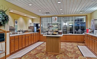 a large dining room with a buffet table and various food items on display , such as sandwiches and desserts at Country Inn & Suites by Radisson, Ft. Atkinson, WI