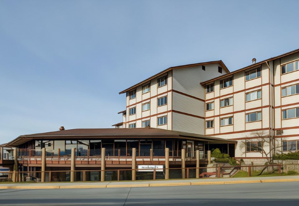 a large , multi - story hotel with a brown roof and white walls , situated on a street at Westmark Sitka