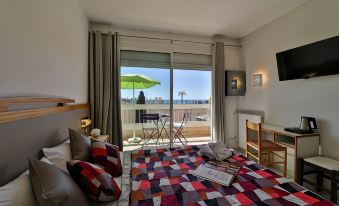 a hotel room with a large bed , a dining table , and a balcony overlooking the ocean at Hotel Restaurant de la Mer