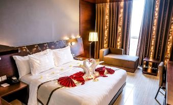 a luxurious hotel room with a king - sized bed adorned with a heart - shaped arrangement of flowers , creating a romantic atmosphere at Aston Imperial Bekasi Hotel & Conference Center