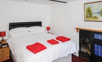 a bedroom with a white bed and red towels on the pillows , next to a fireplace at George Inn