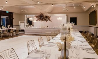 a long dining table is set with gold chairs and a centerpiece of flowers at Joondalup Resort