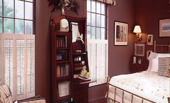 a cozy bedroom with a bed , bookshelves , and window shades , giving it a warm and inviting atmosphere at The White House Inn