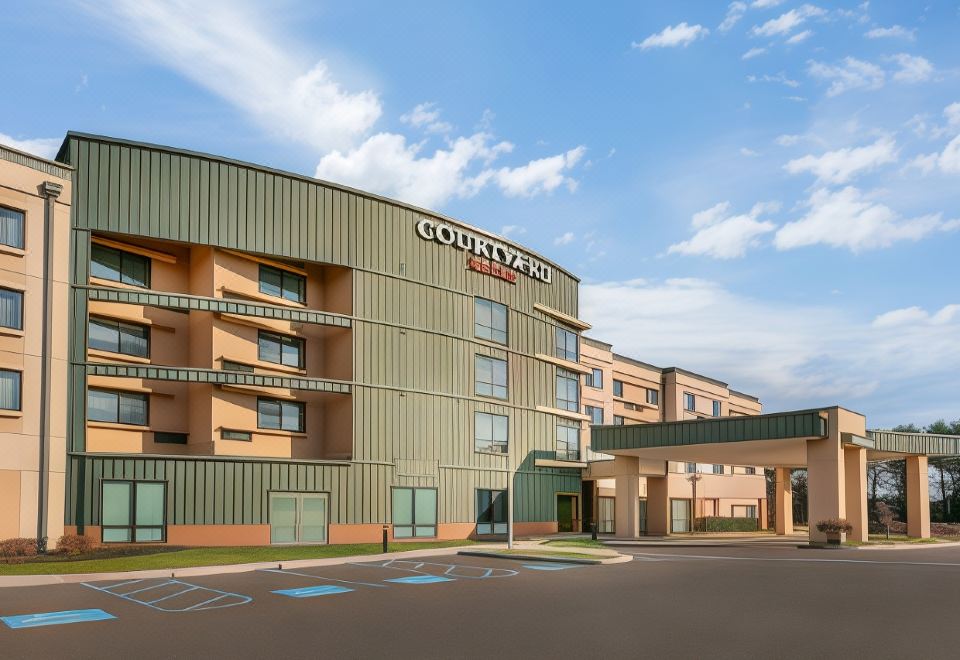 an exterior view of a courtyard by marriott hotel , featuring a large parking lot and a bridge at Courtyard Burlington Mt. Holly/Westampton