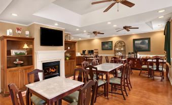 a dining room with wooden tables and chairs , a fireplace , and ceiling fans , providing a cozy atmosphere at Comfort Inn