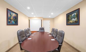 a conference room with a round table surrounded by chairs , and a whiteboard on the wall at Comfort Inn