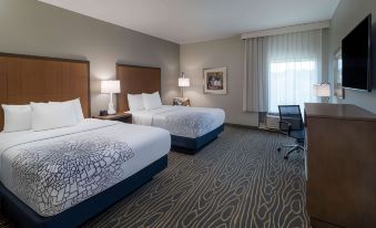 a modern hotel room with two beds , nightstands , and a desk , all neatly arranged in the space at La Quinta Inn & Suites by Wyndham Tifton