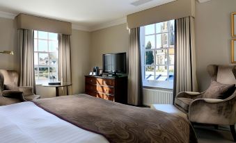a hotel room with a large bed , a tv , and a window overlooking a golf course at Macdonald Compleat Angler