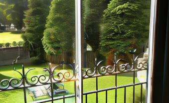 a balcony overlooking a lush green garden , with a view of trees and a swimming pool at Grapes Hotel, Bar & Restaurant Snowdonia Nr Zip World