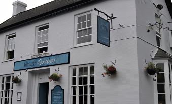 "a white building with two blue signs hanging from the windows , one of which has a sign that says "" ivy "" above it" at The Black Swan