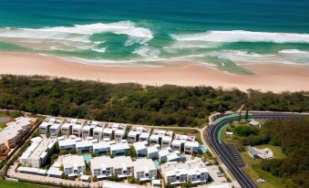 a bird 's eye view of a coastal town with white buildings , green trees , and blue water at Sand Dunes Resort