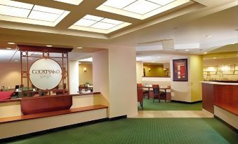 a hotel lobby with a reception desk and chairs , as well as a dining area with tables and chairs at Courtyard Columbus New Albany