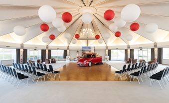 a large room with a red car in the middle and several chairs arranged around it at The Atholl Palace