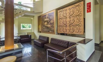 a modern living room with brown leather couches and a staircase , featuring a large painting on the wall at OYO Flagship Hotel Priso