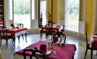 a well - lit dining room with several tables covered in red tablecloths and set for a meal at Hostal la Casona