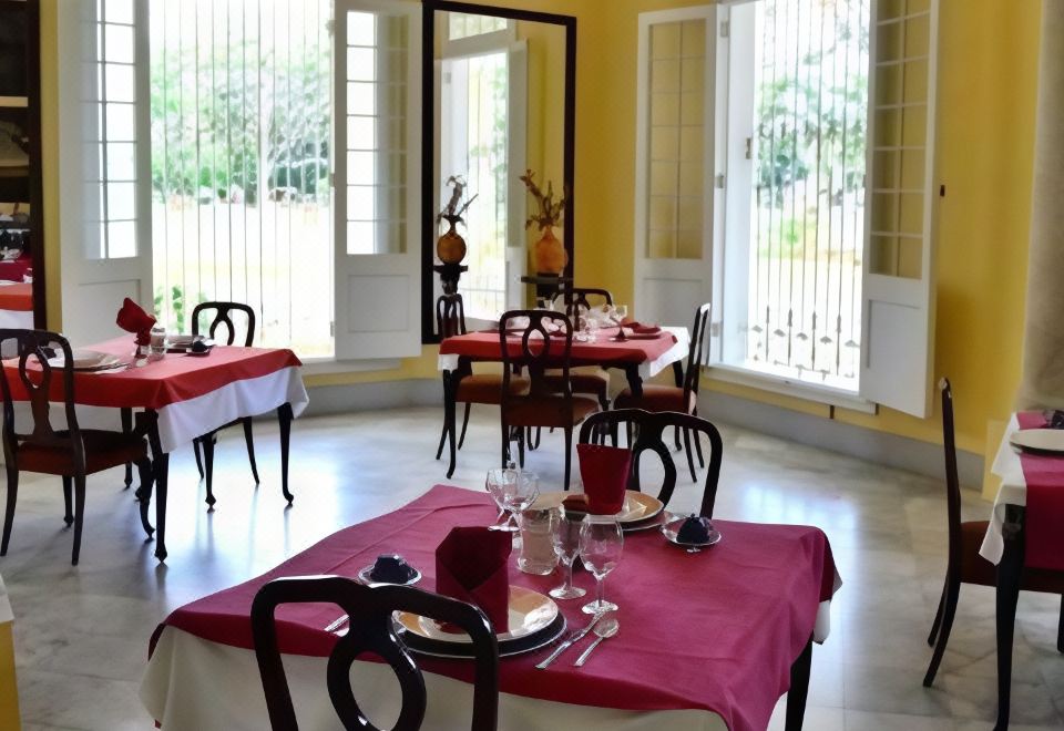 a well - lit dining room with several tables covered in red tablecloths and set for a meal at Hostal la Casona