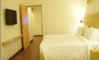 a well - lit hotel room with a bed , tv , and door , giving a clean and spacious appearance at Hotel Midcity