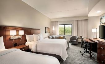 a modern hotel room with two beds , a couch , and a desk , all neatly arranged at Courtyard Middletown Goshen