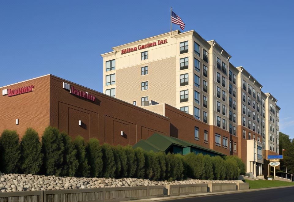 a hilton garden inn hotel with its sign and american flag , situated on a street corner at Hilton Garden Inn Troy