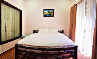 a white bed with a wooden headboard and footboard , topped with two pillows , in a bedroom with a window and a painting on the at Riverside Park Eco Resort