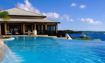 a luxurious villa with a large swimming pool and a waterfall , surrounded by a stunning view of the ocean at Scrub Island Resort, Spa & Marina