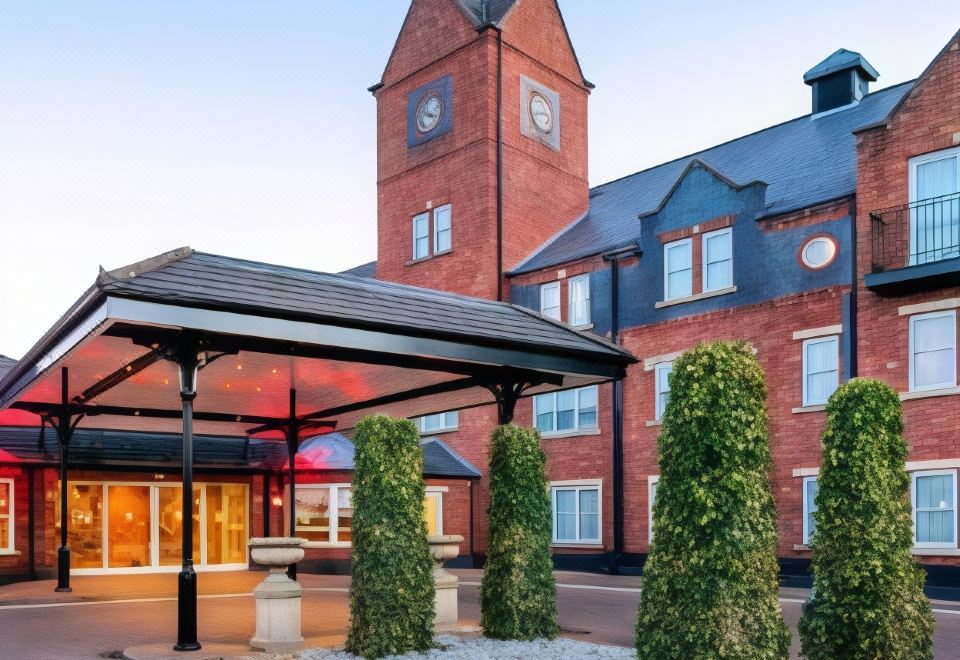 a brick building with a clock tower in the background and a covered walkway leading to the entrance at The Park Royal Hotel & Spa