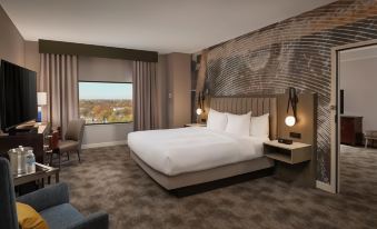a modern hotel room with a large bed , nightstands , and a window offering a view of the city at Hilton Lexington/Downtown