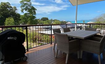 a wooden deck with a table , chairs , and an umbrella is shown overlooking a beach at Island Villas