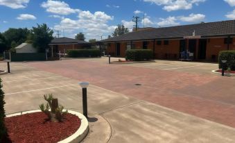 a paved parking lot with several cars parked , including a truck and a van , under a clear blue sky at Adelong Motel