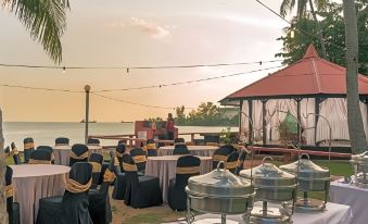 a large outdoor dining area with tables , chairs , and a stage set up for a party or event at Shah's Beach Resort