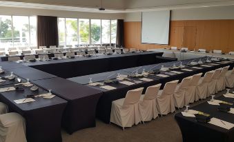 a large conference room with multiple tables , chairs , and a projector screen set up for an event at Chateau Royal Beach Resort & Spa, Noumea