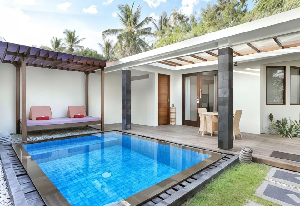 a small swimming pool surrounded by a patio , with lounge chairs and umbrellas placed around it at Aston Sunset Beach Resort - Gili Trawangan