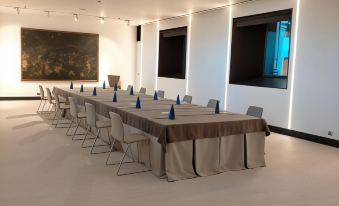 a large conference room with multiple long tables , chairs , and a painting on the wall at Parador de Leon - San Marcos
