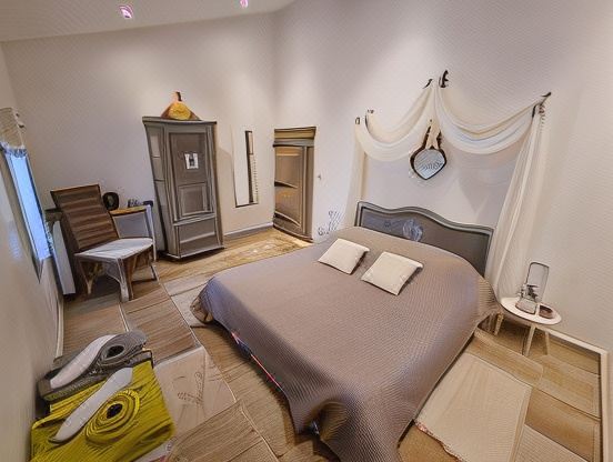 a modern bedroom with a large bed , wooden floor , and various items on the nightstand at La Bastide