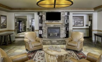 a spacious living room with beige leather chairs , a round table , and a large stone fireplace at Yellowstone Park Hotel