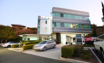 "a modern building with a sign reading "" bondi sands "" and a car parked in front of it" at Springfield Lakes Boutique Hotel